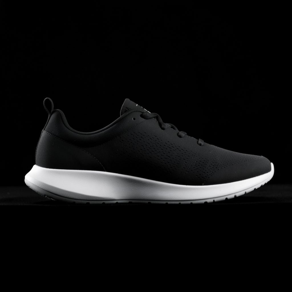 Monochrome side profile of a sleek athletic shoe silhouette against a dark background, highlighting the curved sole